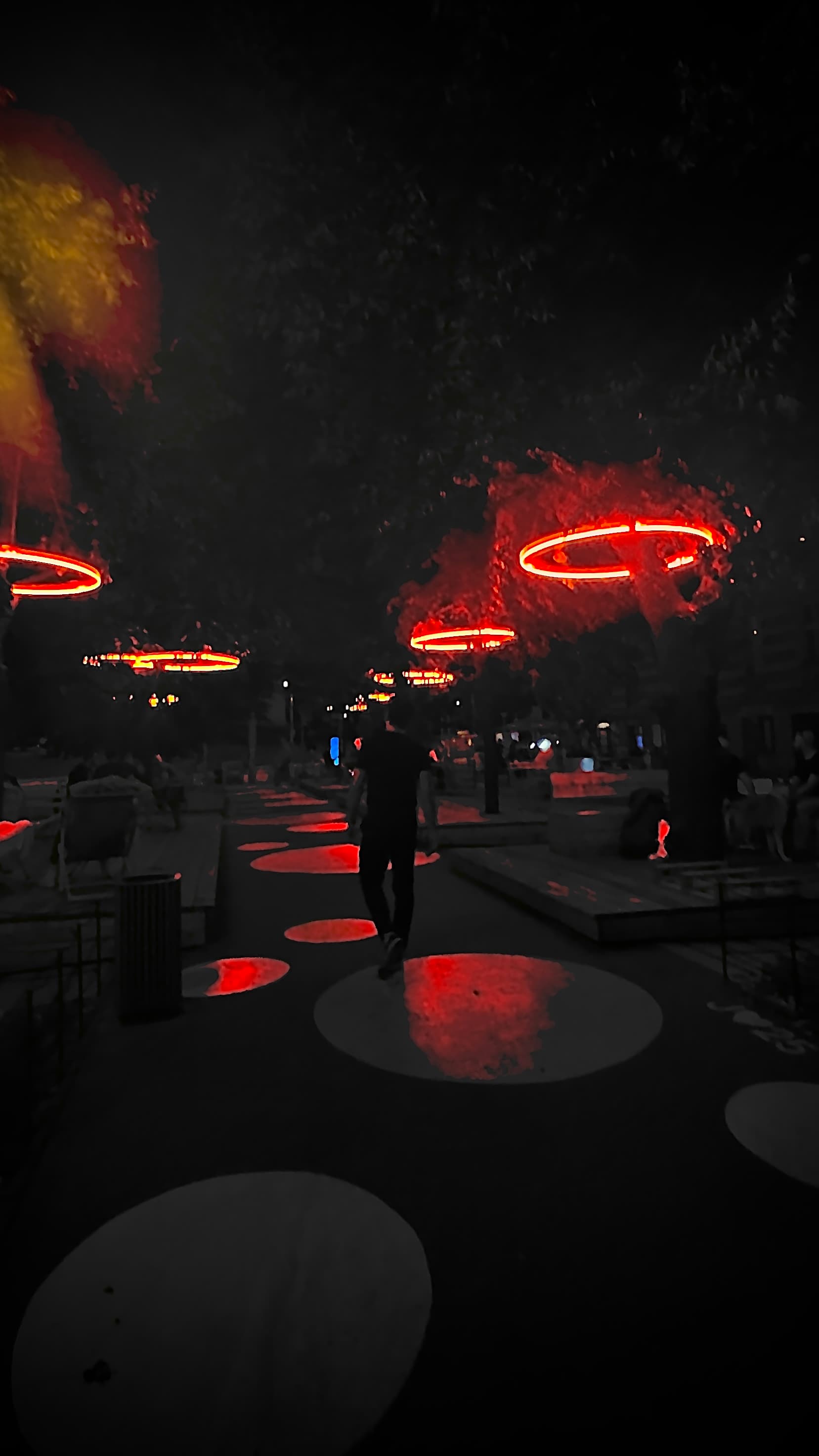 Night image with person in the middle and red lights in the sky.